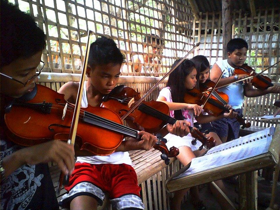 Photo of young musicians playing string instruments. This photo shows students guiding their own rehearsal for the Ang Misyon program on Talim Island in The Philippines.