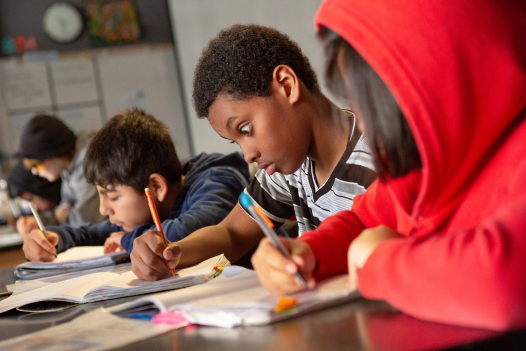 A middle school boy takes notes during a science lesson about the environment. Photo by Allison Shelley for EDUimages