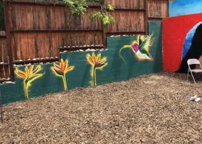 Image of a mural made during Restorative Justice for the Arts' Summer Mural Youth Program. The mural shows a hummingbird and some flowers.