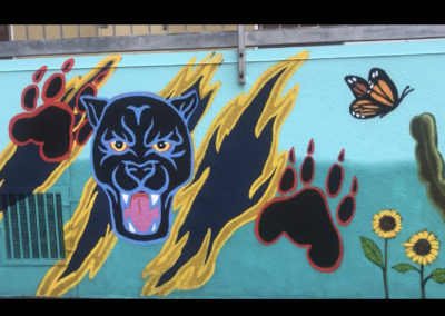 Image of a mural made during the Yorkdale Elementary Mural Project. The image shows a black panther with paw prints and some butterflies and flowers.