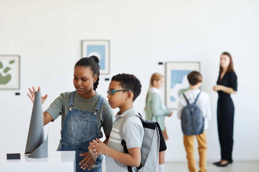 Minimal portrait of schoolchildren visiting art gallery and looking at modern sculptures