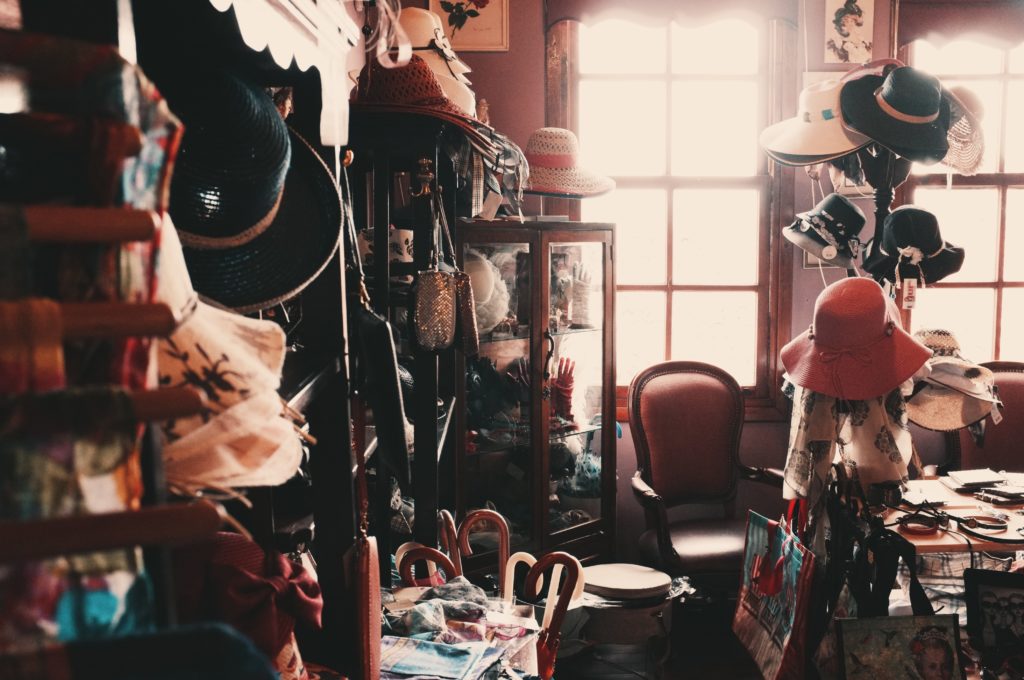An assortment of different styles of hats among other items in an eclectic vintage room.